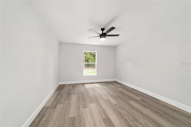 an empty room with a window and a ceiling fan