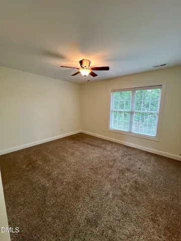 an empty room with a ceiling fan and window