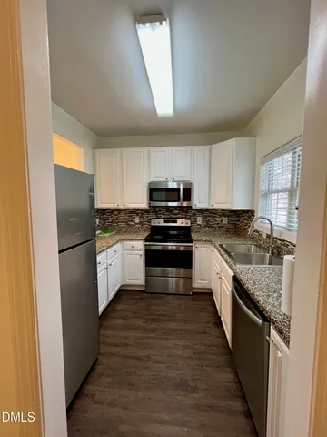 a kitchen with granite countertop a refrigerator stove top oven and cabinets
