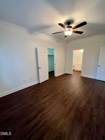 a view of an empty room with wooden floor and a ceiling fan