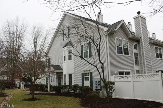 a view of a white house next to a yard with big trees