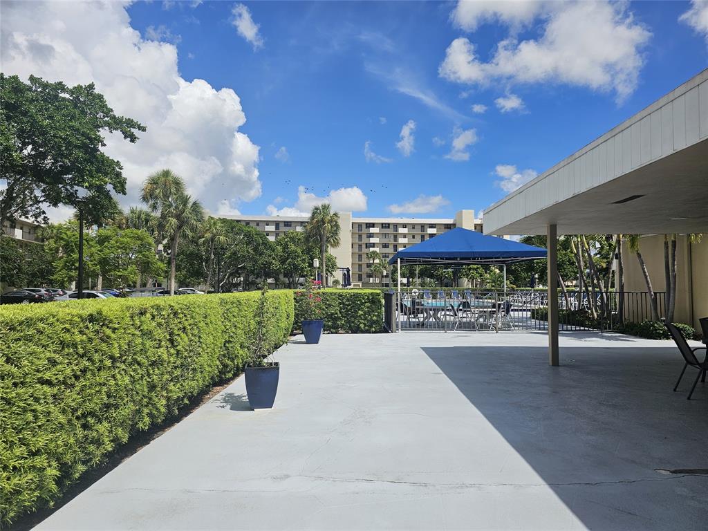 2450 DC Country Club Boulevard, Unit 203B Deerfield Beach, FL 33442 - Photo 11 of 19 a view of a patio with a table and chairs under an umbrella