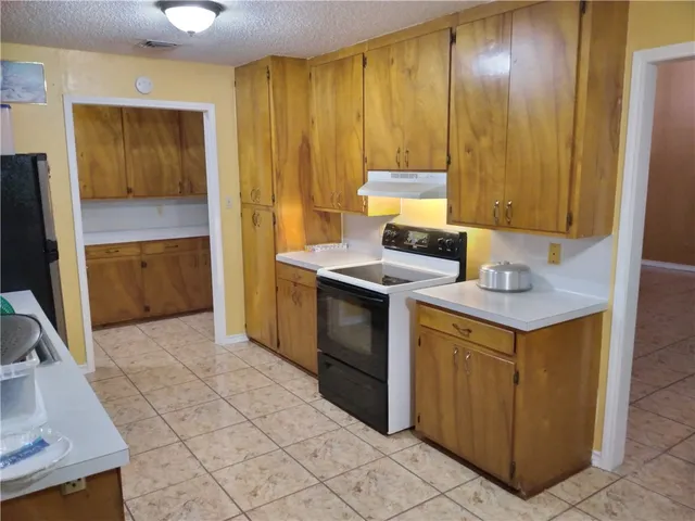 a kitchen with granite countertop a stove a sink and a refrigerator