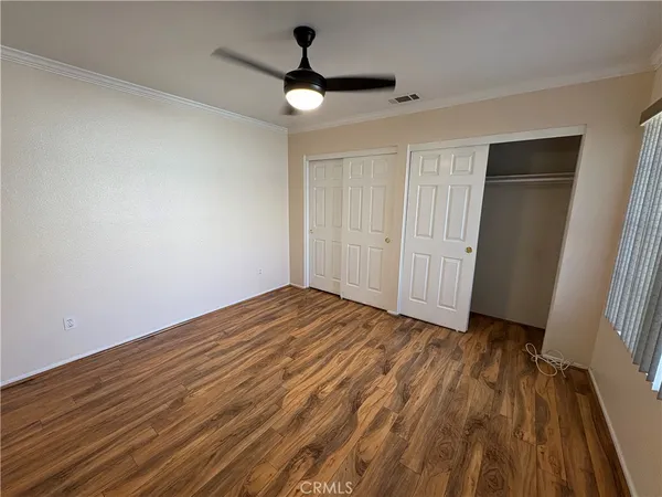 a view of empty room with wooden floor and fan