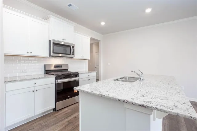 a kitchen with granite countertop a sink and steel appliances