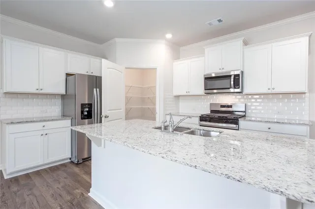 a kitchen with stainless steel appliances granite countertop a stove a sink a refrigerator a microwave and cabinets