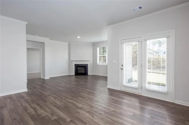 an empty room with wooden floor fireplace and windows