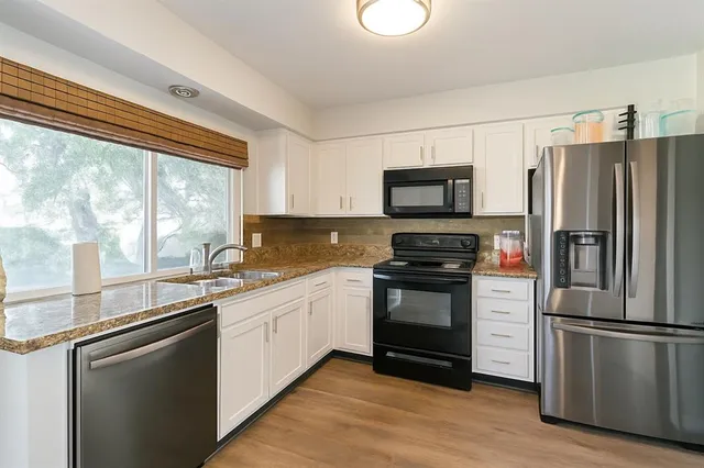 a kitchen with granite countertop a refrigerator stove and sink