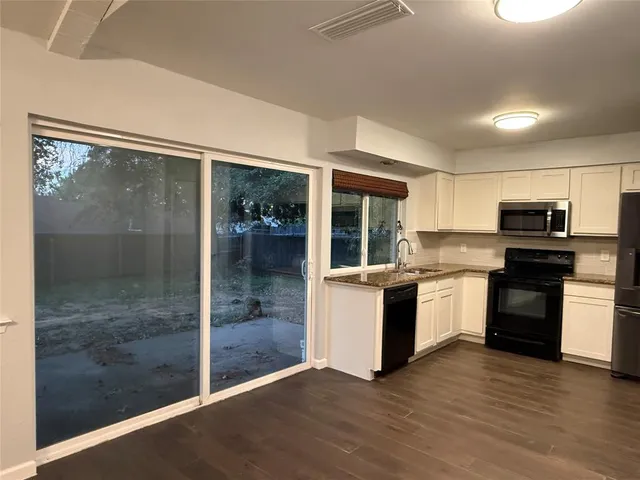 a large kitchen with kitchen island a counter top space a sink stainless steel appliances and cabinets