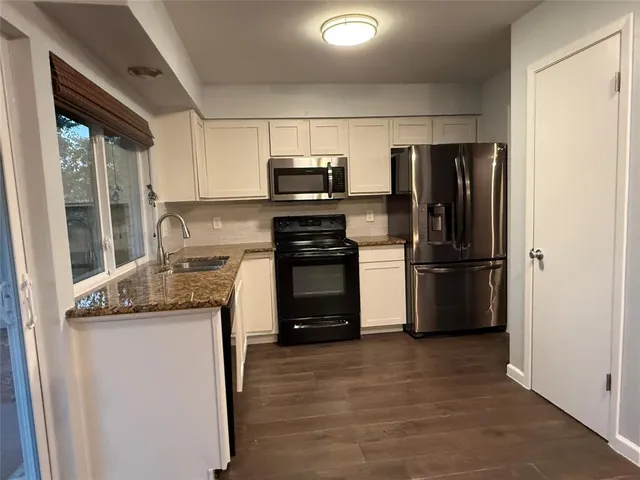 a kitchen with granite countertop a refrigerator and a stove top oven