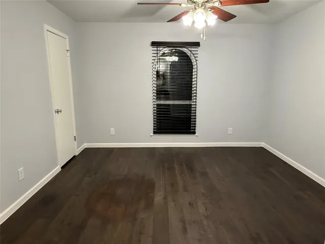 an empty room with a chandelier fan and windows