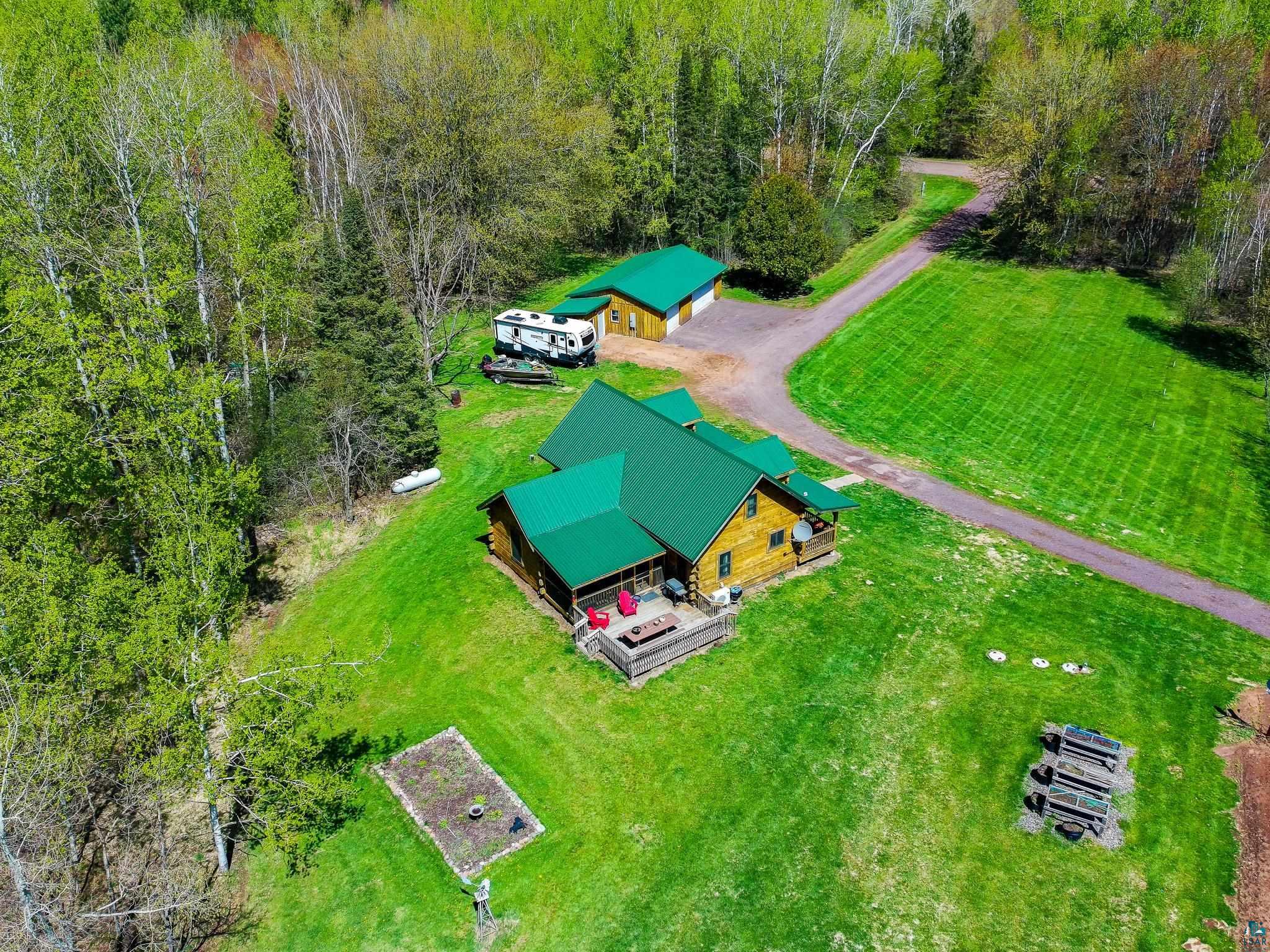 37590 Degerstrom Road Askov, MN 55704 - Photo 43 of 53 Log-sided residence featuring a vibrant green metal roof, an expansive deck, and a detached two-car garage