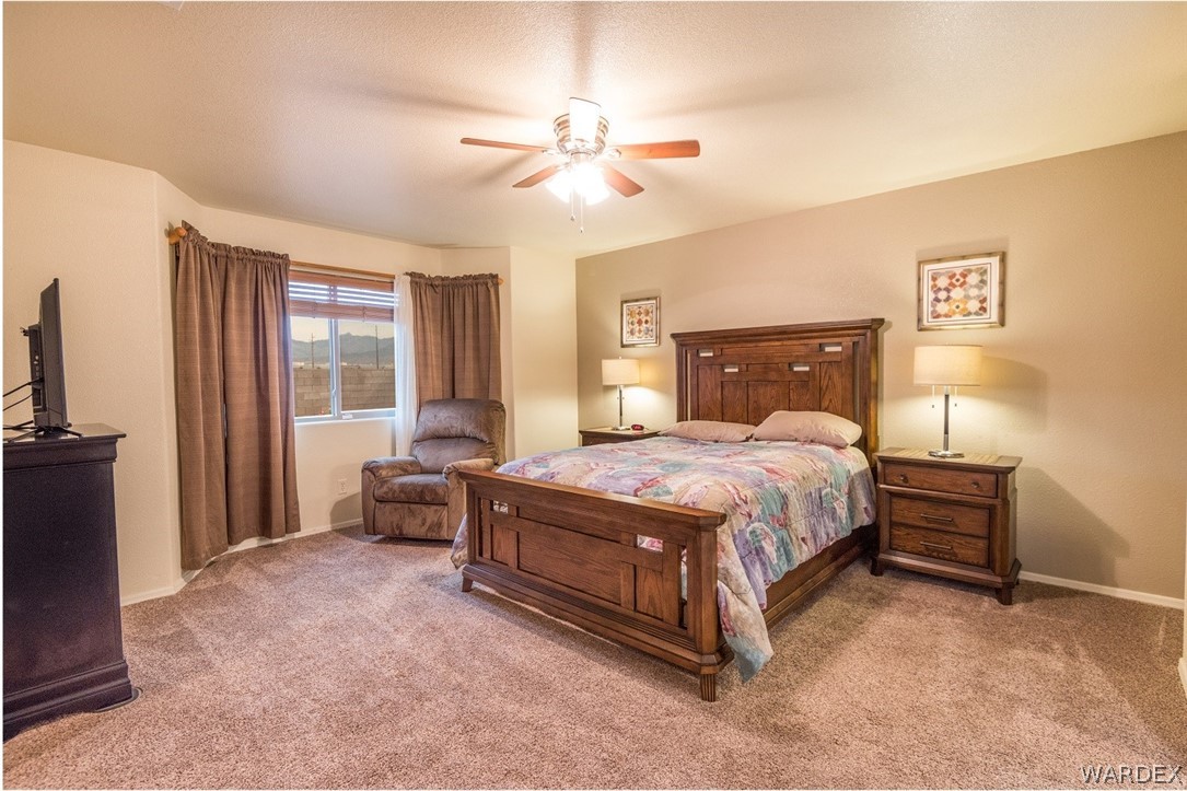 4292 East Cane Ranch Road Kingman, AZ 86401 - Photo 13 of 34 a spacious bedroom with a bed and a chandelier