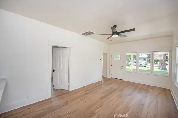 a view of an empty room with wooden floor and a window