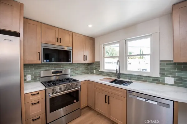 a kitchen with granite countertop a sink cabinets stainless steel appliances and a counter top space