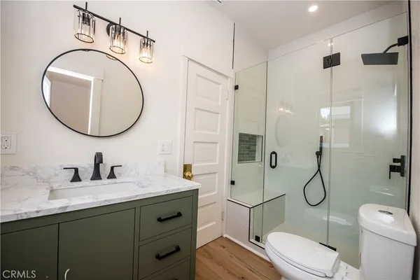 a bathroom with a toilet sink vanity granite and shower