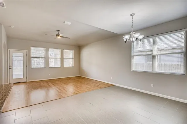 an empty room with chandelier fan and windows