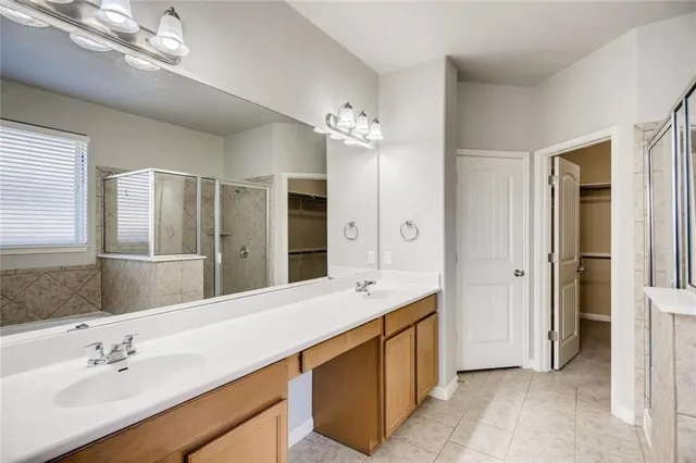 a spacious bathroom with a double vanity sink a mirror and a shower