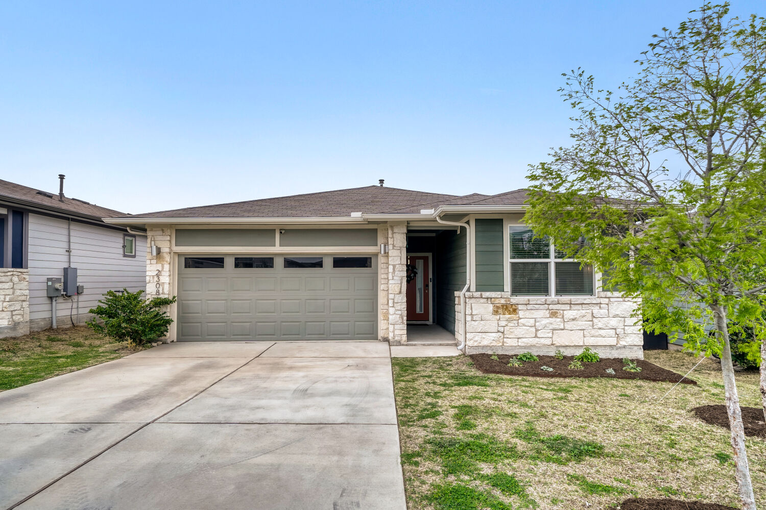 2308 Ranier Court Austin, TX 78754 - Photo 2 of 29 Single story home featuring stone siding, concrete driveway, a garage, a front lawn, and roof with shingles