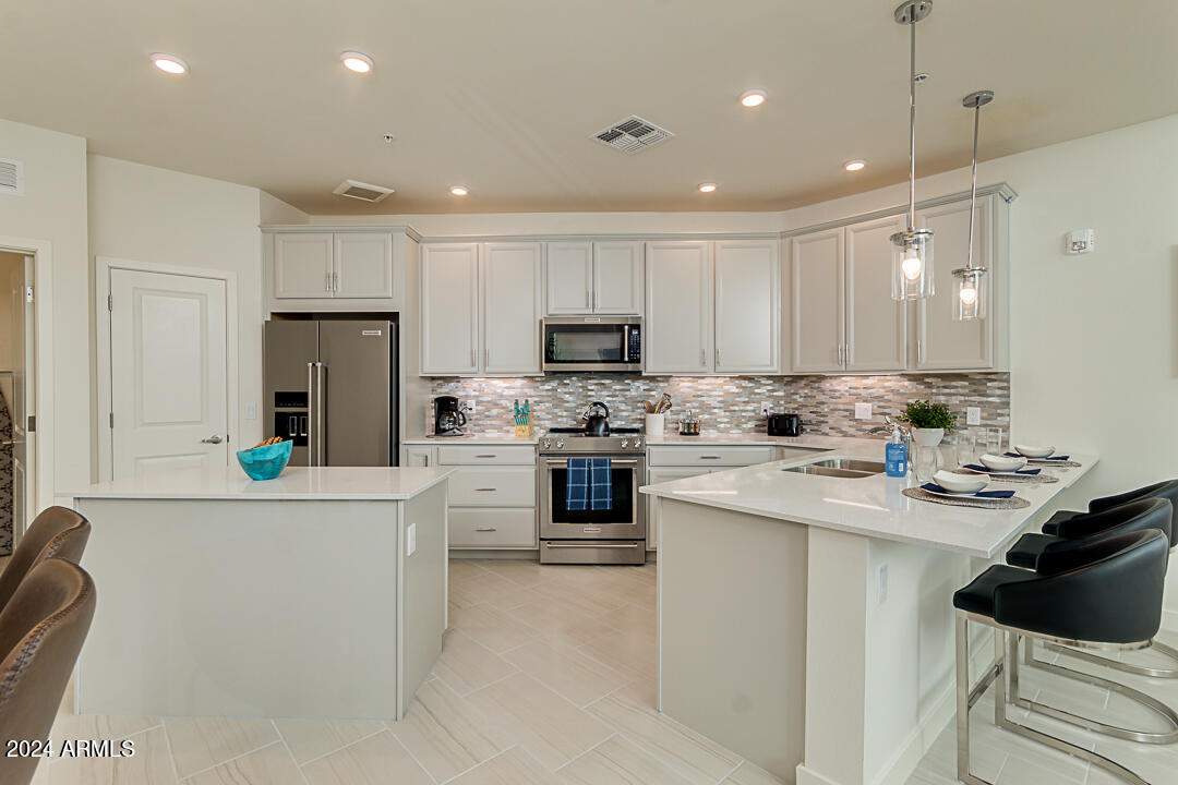 2511 West Queen Creek Road, Unit 416 Chandler, AZ 85248 - Photo 11 of 30 a kitchen with white cabinets and stainless steel appliances