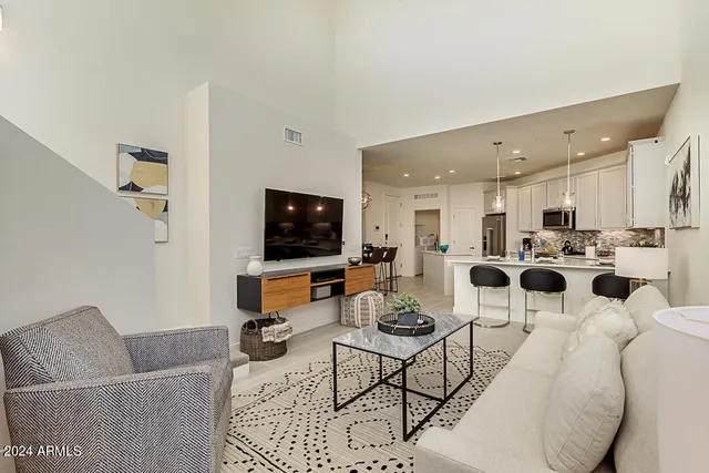 a living room with furniture kitchen view and a flat screen tv