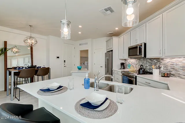 a kitchen with stainless steel appliances kitchen island granite countertop a dining table and chairs