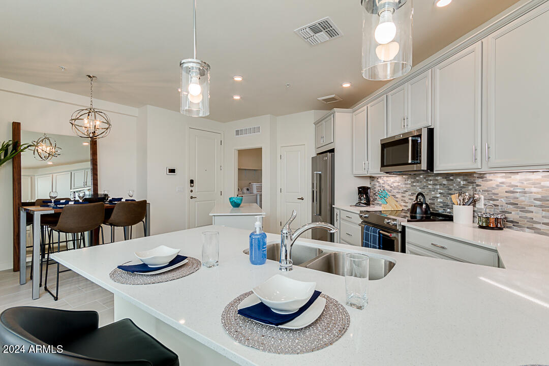 2511 West Queen Creek Road, Unit 416 Chandler, AZ 85248 - Photo 10 of 30 a kitchen with stainless steel appliances kitchen island granite countertop a dining table and chairs
