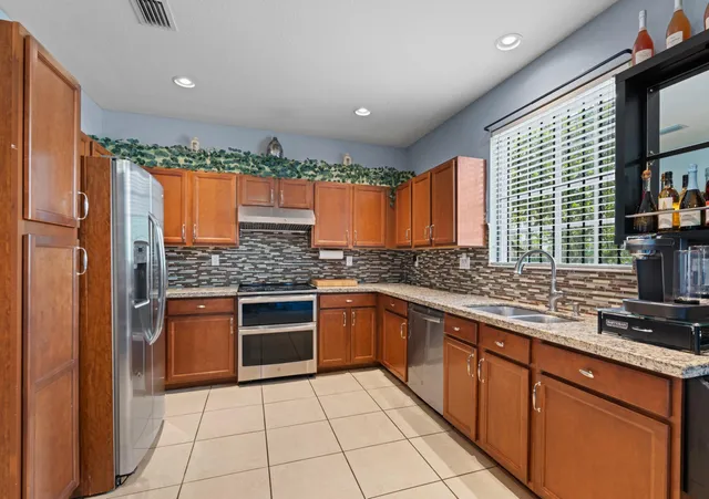 a kitchen with stainless steel appliances granite countertop a stove a sink and a refrigerator