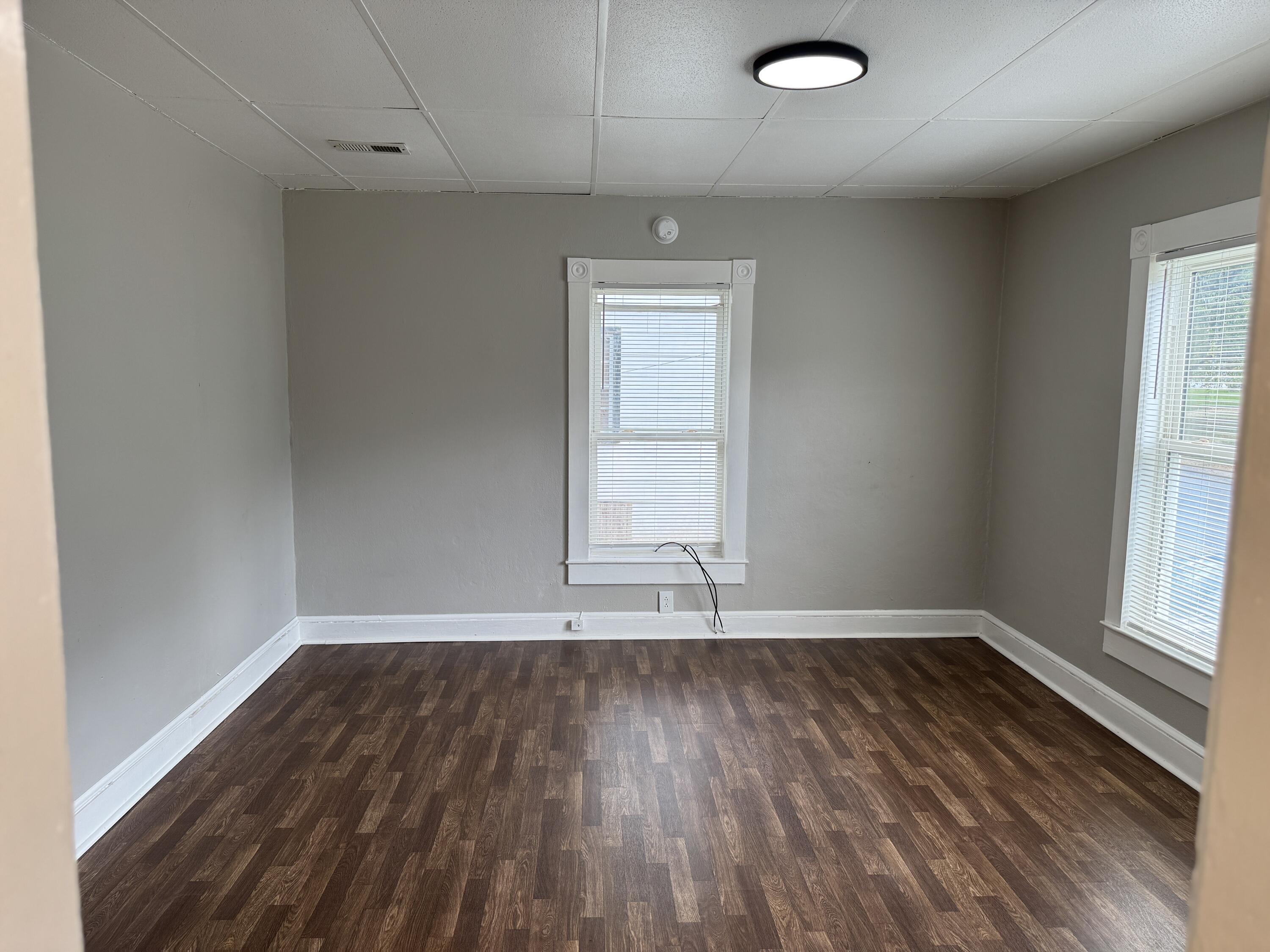 1006 Halifax Road Danville, VA 24540 - Photo 3 of 7 an empty room with wooden floor and windows