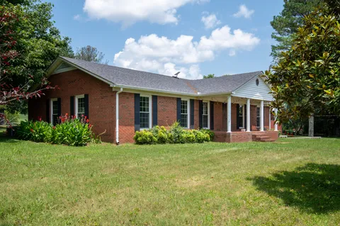 a view of a house with a big yard and large tree