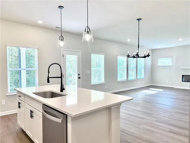 a kitchen with stainless steel appliances granite countertop a sink a center island and a wooden floor