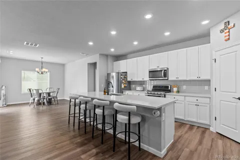 a kitchen with stainless steel appliances a table chairs refrigerator microwave and cabinets