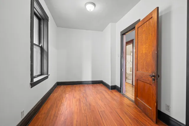 an empty room with wooden floor and a window