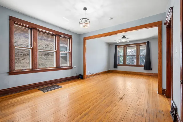 a view of an empty room with window and wooden floor