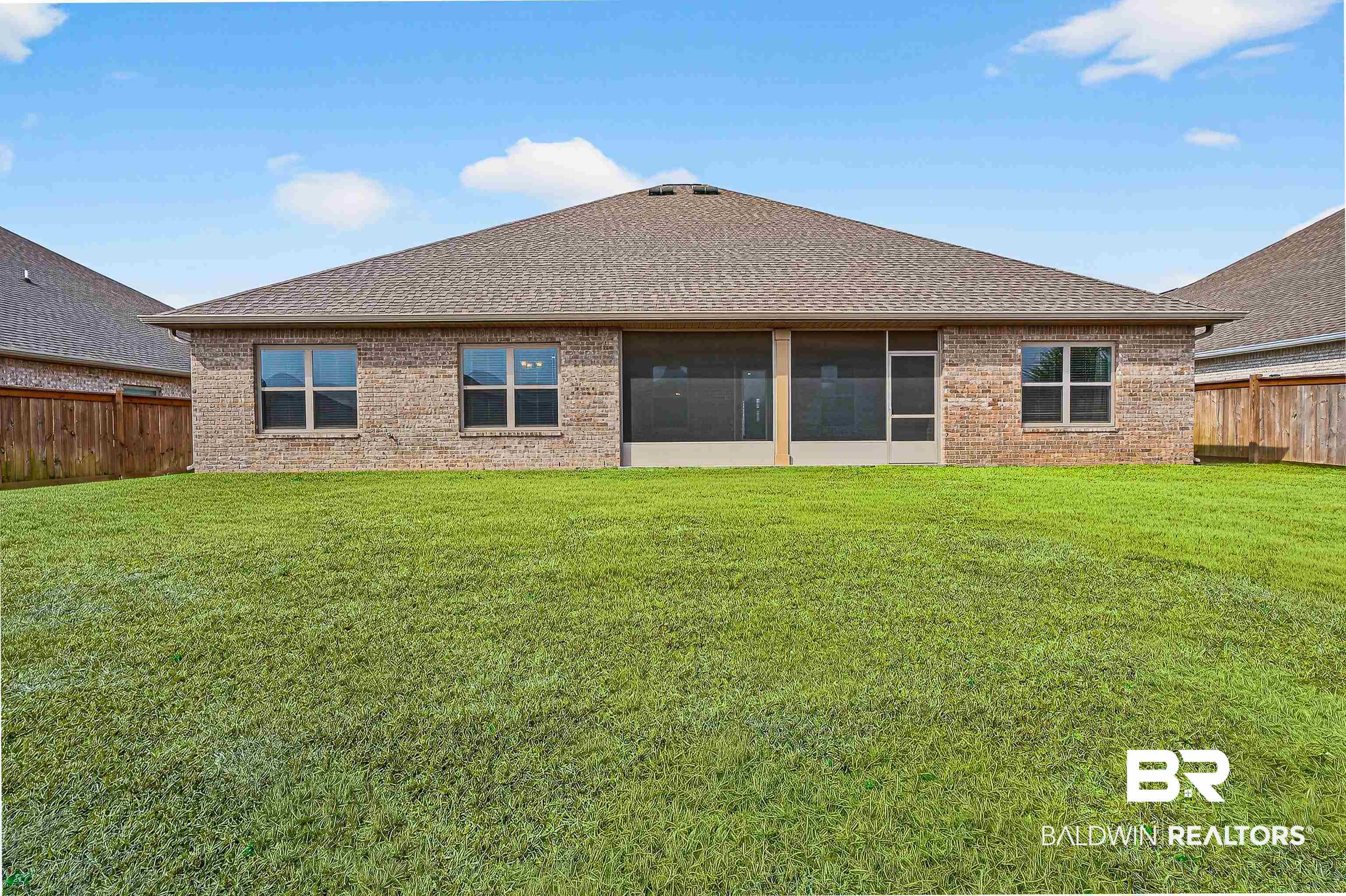 1728 Partridge Street Foley, AL 36535 - Photo 3 of 37 Expansive backyard featuring a manicured lawn, brick exterior, multiple windows, a screened patio, and a shingled roof