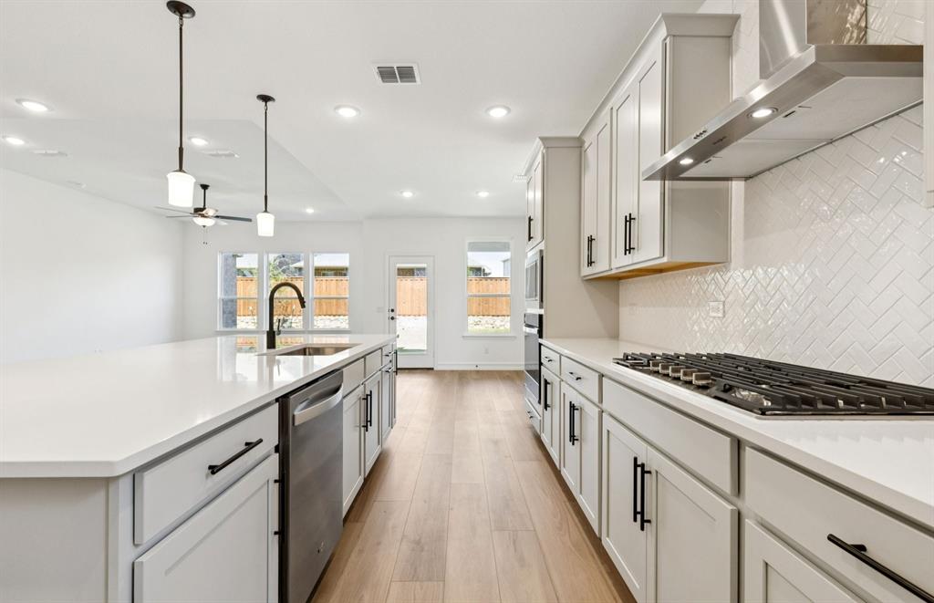 304 Brookhurst Road Little Elm, TX 75068 - Photo 4 of 22 a kitchen with stainless steel appliances a sink a stove top oven a counter space and cabinets