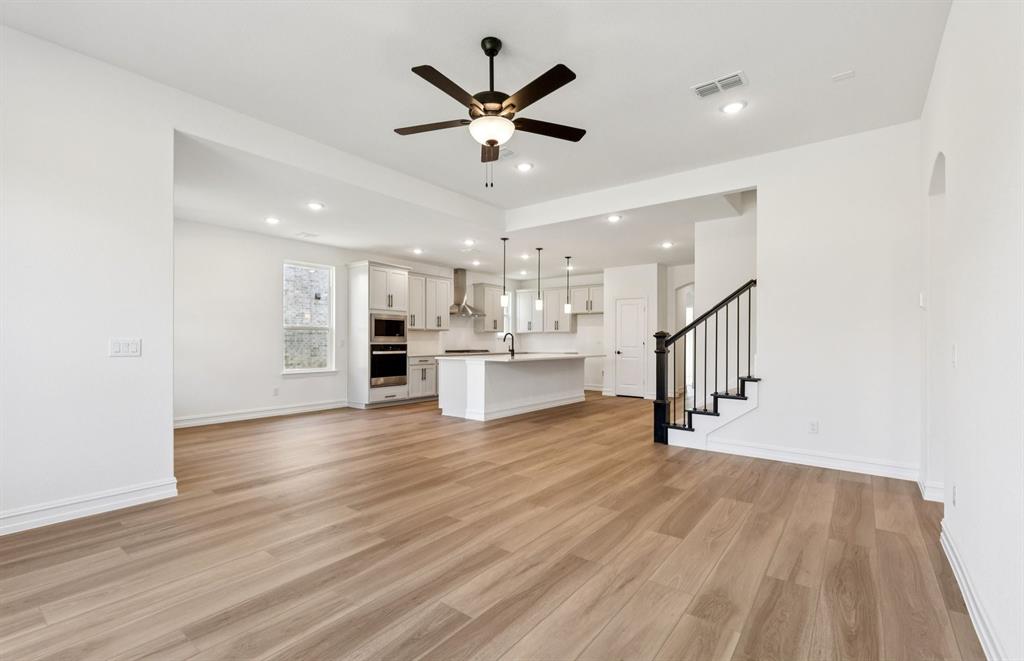 304 Brookhurst Road Little Elm, TX 75068 - Photo 7 of 22 a view of an empty room with wooden floor and a ceiling fan