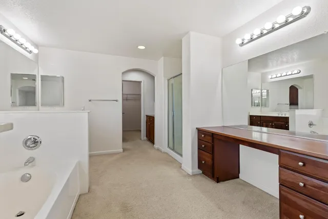 a spacious bathroom with a tub sink and mirror