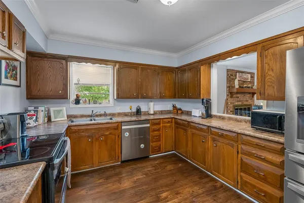 a kitchen with stainless steel appliances granite countertop a sink dishwasher stove and wooden cabinets