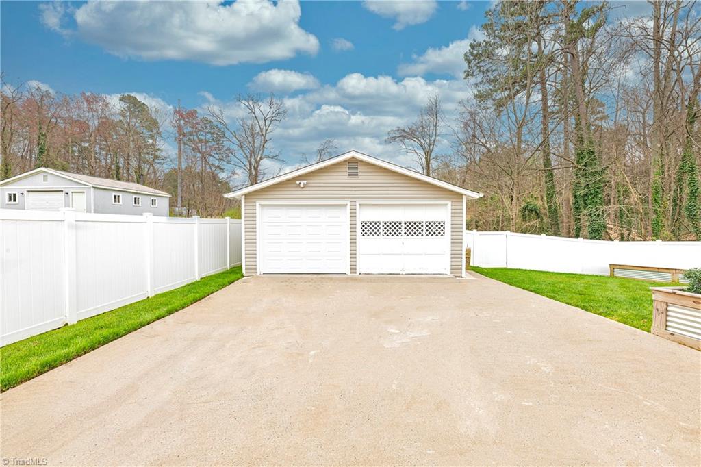 Back Yard Driveway Area. (New garage door on left in picture. Garage door on right is in operable. Previous owner built a workbench on door)