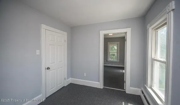 a view of an empty room with closet and a window