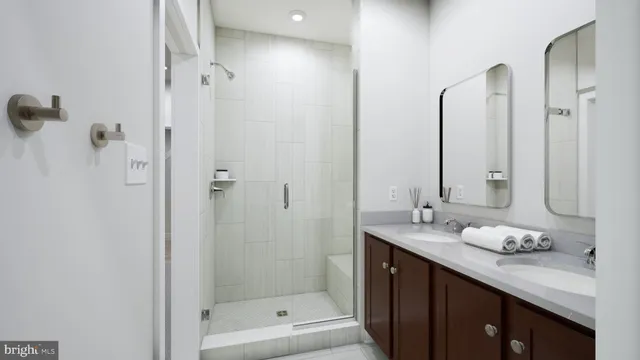 a bathroom with a granite countertop sink two mirror and shower
