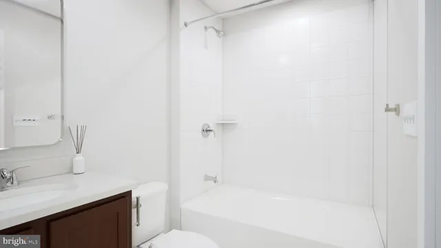 a bathroom with a granite countertop bathtub shower sink vanity and toilet