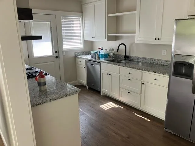 a kitchen with granite countertop white cabinets white appliances a sink and dishwasher