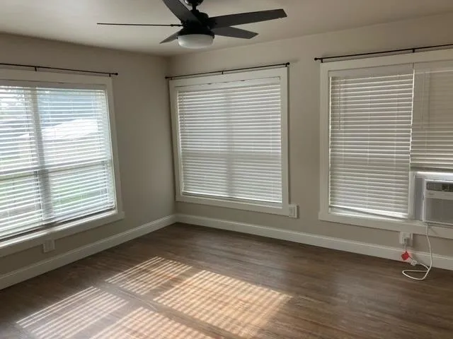 a view of an empty room with a window and wooden floor