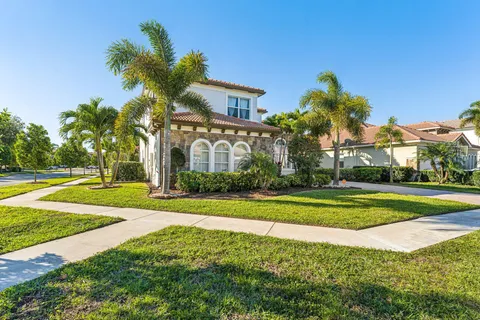 a view of a white house with a yard and palm trees