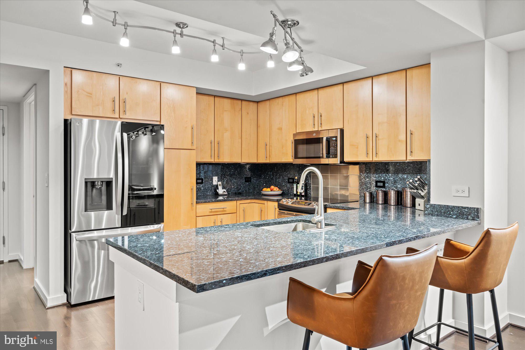 1025 First Street Southeast, Unit 511 Washington, DC 20003 - Photo 5 of 25 a kitchen with stainless steel appliances granite countertop a stove top oven a refrigerator a sink dishwasher a dining table and chairs with wooden floor