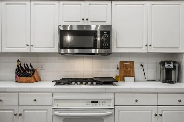 a kitchen with white cabinets and a stove top oven