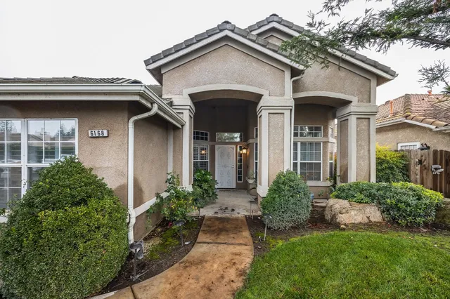 a view of a white house with a small yard and plants