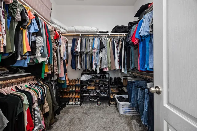 a view of walk in closet with clothes and shoes